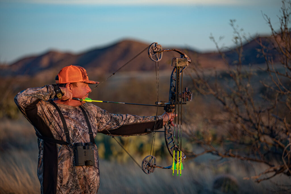 A man with a bow and arrow at home.