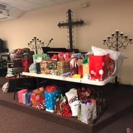 A table full of Christmas presents in a church, creating a festive atmosphere in this spiritual home.